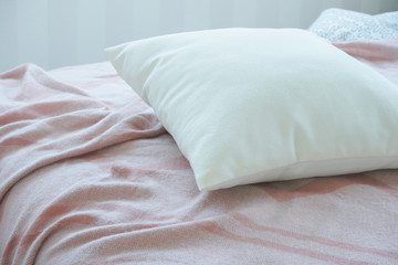 Fototapeta na wymiar White pillow on pink messy bed