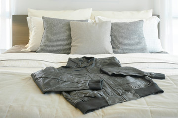 Gray pillows and black leather jacket on bed
