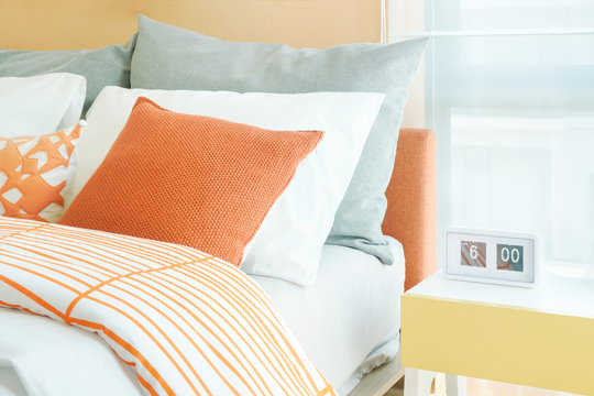 Modern style alarm clock on night table next to bed, lively style bedding color scheme