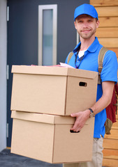 Smiling delivery man in blue uniform delivering parcel box to recipient - courier service concept