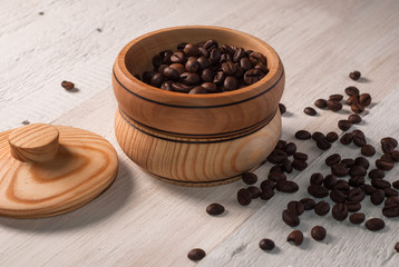 A wooden bowl with coffee beans on old wooden table,