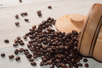 Fototapeta premium Coffee beans scattered from a Cup on white wooden background, wooden utensils,