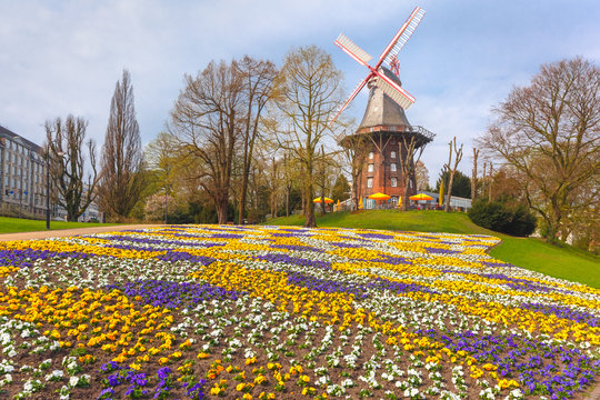 Popular city park Wallanlagen with Am Wall Windmill and colorful flowers foreground in Bremen, Germany