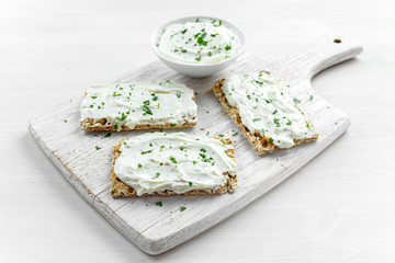 Homemade Crispbread toast with Cream Cheese and parsley on white wooden board background.
