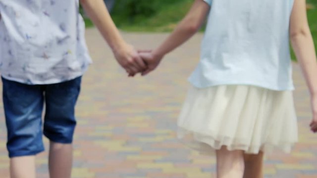 A Little Girl And Boy Hold Hands And Run Down Scenic Beach Path