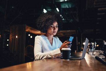 Businesswoman working late and using mobile phone