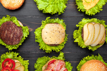 Ingredients for burger. Nine burgers in different stages of readiness. view from above. Black wood background