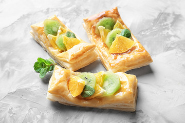 Delicious puff pastries with fruits and honey on grey background