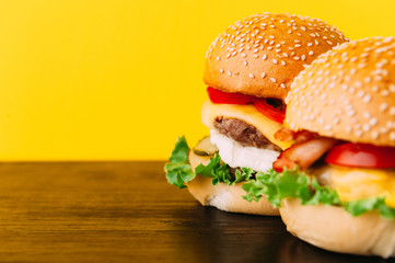 Bright juicy appetizing burgers with chops, cheese, marinated cucumbers, tomatoes and bacon