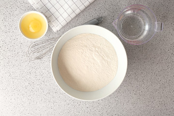 Flour, egg and water in kitchenware on grey table