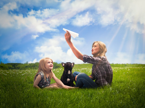 Lucky kids launch paper airplane. Green grass, blue sky, the rays of the sun. Girls play