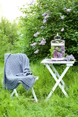 Küchenrückwand glas motiv Cage with lilac flowers on table in beautiful garden © Africa Studio