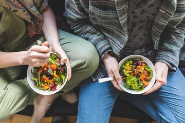 Fotobehang Paar dat gezonde salade thuis op de bank eet © william87