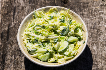 Spring salad with cabbage, cucumber, green onion, parsley and mayonnaise on wooden table