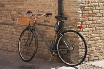 Fototapeta na wymiar Vintage bike for picnic stands near the brick wall of Italian city.