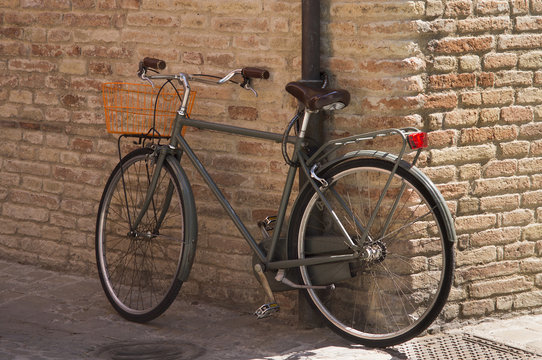 Vintage bike for picnic stands near the brick wall of Italian city.