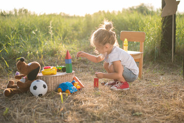 toddler girl playing with toys on nature