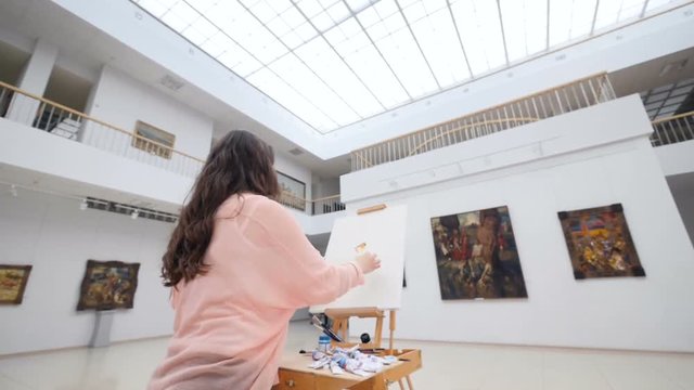 Female artist painting a picture in art gallery.