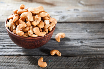 raw cashew nuts in ceramic bowl on wood table