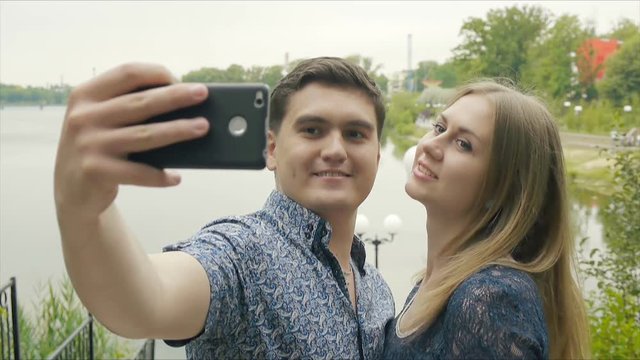 Romantic couple walking in the Park at sunset and makes a selfie.