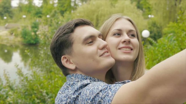 Romantic couple walking in the Park at sunset and makes a selfie.