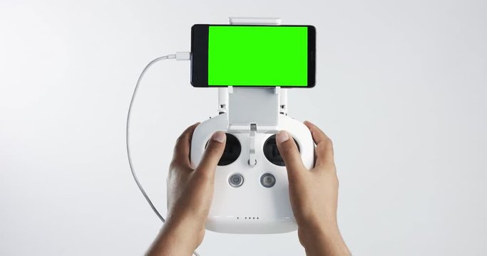 man holding a cuadrocopter control remote and using a smartphone with green screen