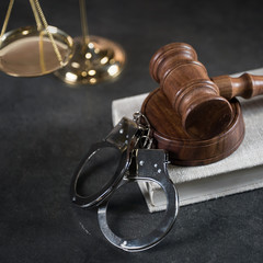 Handcuffs and gavel on dark rustic table