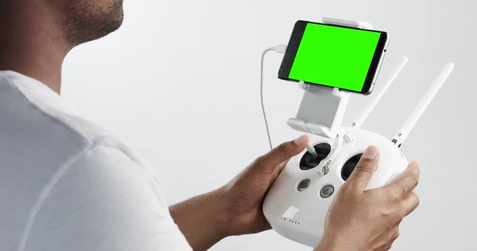 man holding a cuadrocopter control remote and using a smartphone with green screen