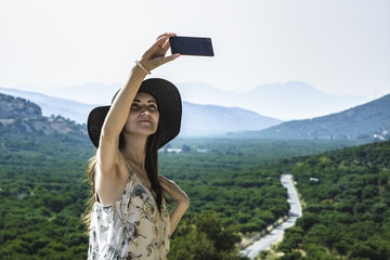 Woman traveler makes a self in the background beautiful natural view mountain on the island of Crete. Concept - tourism, travel, photos from vacation