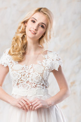 Fototapeta na wymiar fashionable wedding dress, beautiful blonde model, bride hairstyle and makeup concept - young smiling woman in white gown indoors on light background, luxury female posing in the studio