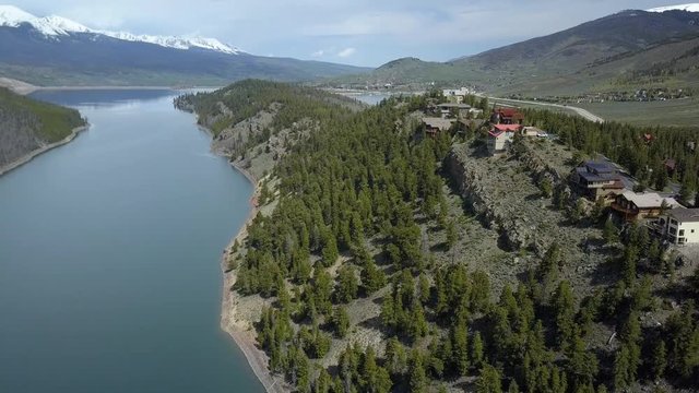 Aerial Dillon Lake luxury homes cliff shoreline pull back. On I-70 interstate freeway west of Denver. Winter and summer resort and recreation area. Dillon Reservoir lake.