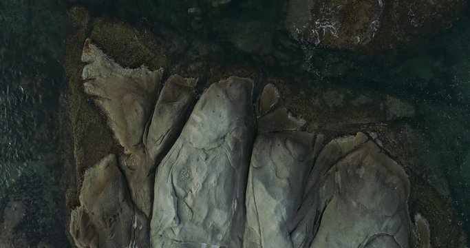 Top view showing plane rocks and a transparent clean sea water with a water-plants in it moving