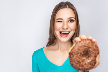 Portrait of beautiful girl with chocolate donuts. winking and looking at camera. studio shot on light gray background.