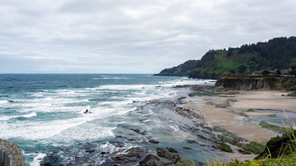 Landscape of an Oregon beach between Coss Bay and Charleston, featuring rocks and a cloudy sky
