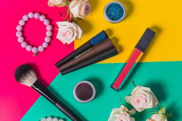 Obraz na płótnie Canvas beautiful professional makeup tri-color on a bright background, roses, lipstick, eyeshadow, mascara, close-up
