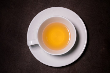 Chrysanthemum herbal tea in white cup on wooden table.
