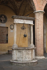 Old well with motto Micat in Vertice in the courtyard of Palazzo Chigi-Saracini, SIena, Tuscany,...