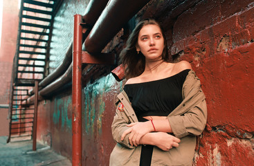 young female looks right in military style jacket near red concrete wall, film photo