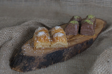 Presentation of Tradional Turkish Baklava with Cocunut and Chocolate Baklava with Pistachio on Wooden Plate