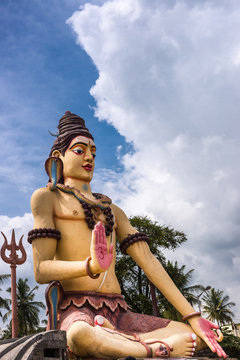 Nanjangud, India - October 26, 2013: Isolated giant Lord shiva statue off Srikanteshwara Temple against blue sky with white clouds. Multicolor and with cobra snake, named Vasuki. 