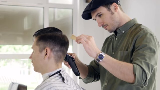 A man sits for a undercut styling. 