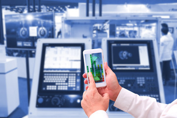 industry 4.0 ,  concept  of Man hand holding tablet with Augmented reality screen software and blue tone of automate wireless Robot arm in smart factory background. mixed media