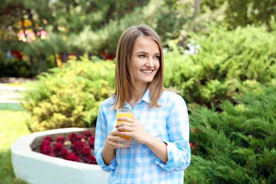 Young beautiful woman with fresh juice in park
