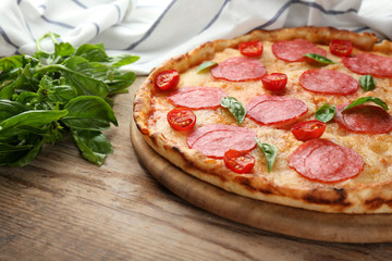 Pizza with salami on wooden table closeup