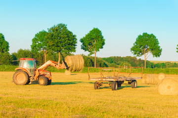 The tractor collects hay on the field