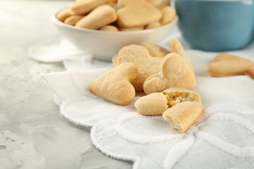 Butter cookies in shape of heart and cup on table