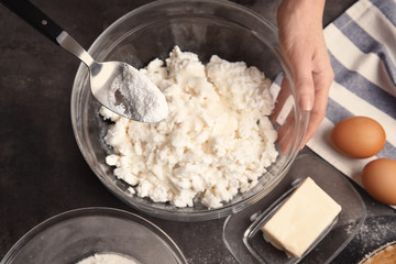 Woman making tasty cheesecake on kitchen