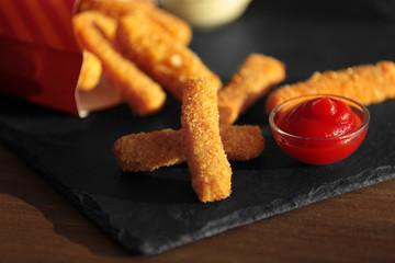 Tasty cheese sticks and sauce on slate plate