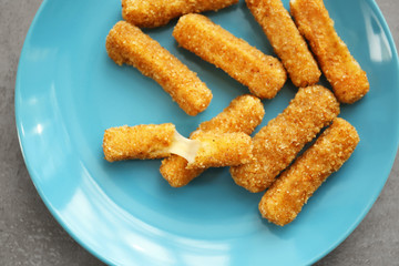Plate with cheese sticks on table