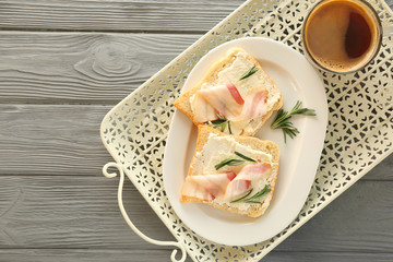 Tasty toasts with bacon and cup of coffee for breakfast on tray